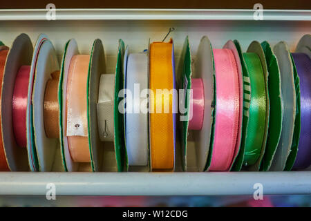 Nastri colorati per ricamo su bobine in negozio. Foto Stock