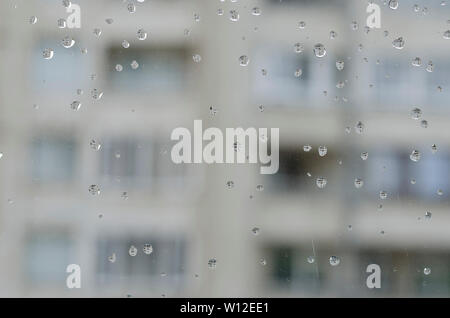 Le gocce di pioggia sulla vettura verso la parte anteriore del vetro laterale Foto Stock