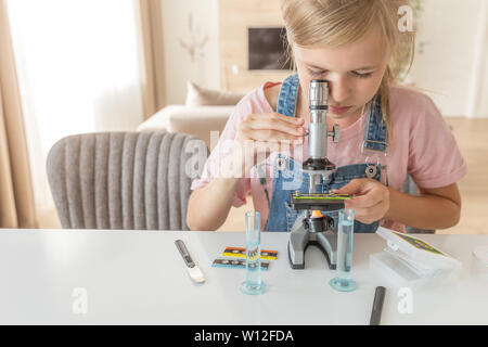 Ragazza di chimica di apprendimento giocando con il microscopio a casa Foto Stock