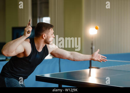 Uomo con tavolo da ping pong racchetta, colpire la palla in azione Foto Stock