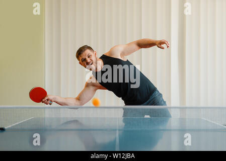 Uomo con tavolo da ping pong racket gioca la palla off Foto Stock