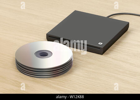 Pila di dischi ottici esterni e unità ottica con slot di caricamento sulla tavola di legno Foto Stock