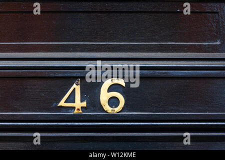 Casa numero 46 con il forty-sei in cifre di metallo su un dipinto di nero in legno antico porta anteriore Foto Stock