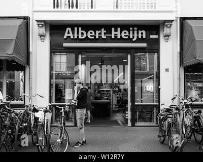 Haarlem, Paesi Bassi - 20 AGO 2018: vista frontale di Albert Heijn olandese della catena di supermercati, fondata nel 1887 a Oostzaan, Paesi Bassi su Kruisstraat 10 Street con il giovane uomo in bianco e nero Foto Stock