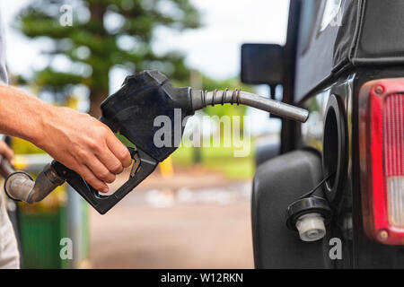 Stazione di gas pompa. Uomo di riempimento carburante benzina in auto ugello di tenuta. Close up. Foto Stock