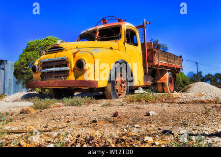 Vecchio arrugginito abbandonato pickup truck sulla terra rossa di raggiungere con opale nero minerali in zone aride climiate di remote NSW - Lightning Ridge opal città mineraria su un caldo Foto Stock