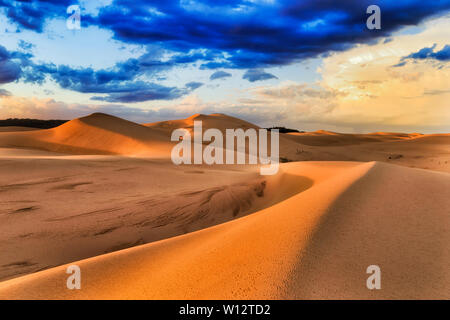 Dark nuvole temporalesche durante ranes su deserta esanime dune di sabbia di Stockton Beach sulla costa del Pacifico in Australia. Masse di sabbia asciutta formando terra wav Foto Stock