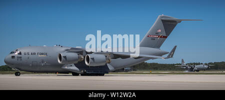 Una C-17 Globemaster III aeromobile dal West Virginia Air National Guard taxi sulla linea di volo mentre un Kentucky Air National Guard C-130 Hercules aeromobile atterra dietro di esso al Alpena Combat Readiness Training Center in Alpena, Mich Entrambi sono degli aerei che trasportano gli avieri dal Kentucky's 123Airlift Wing, che partecipano in esercizio canna carbonizzato. L'esercizio si potranno testare l'unità la capacità di distribuire, sopravvivere e operare sotto simulate condizioni ostili pur fornendo sostegno militare a un alleato fictional, migliorando la reale fattibilità del mondo per ogni Airman. (U.S. Air National Guard phot Foto Stock