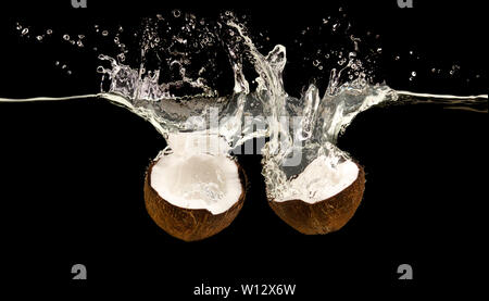 Mature le due metà di noce di cocco con acqua splash e scende Foto Stock