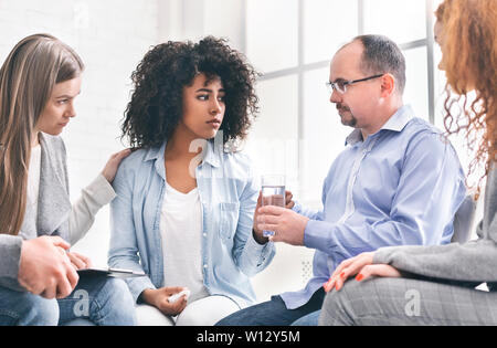 Gentili persone consolante donna africana al gruppo di supporto Foto Stock