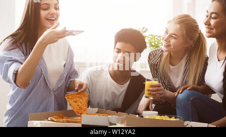 Giovani blogger prendendo foto di pizza, avente festa con gli amici Foto Stock