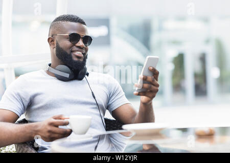 Elegante African American uomo a bere caffè e chat Foto Stock