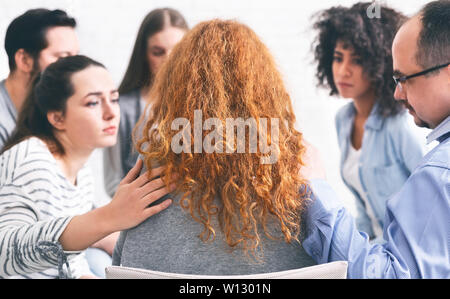 Persone Compassionevoli consolante premuto donna alla riunione di supporto Foto Stock