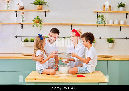 La famiglia felice per la cottura dei biscotti insieme nella cucina di casa Foto Stock