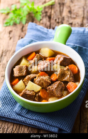 Freschi Fatti in casa stufato di manzo con carote e patate servita nella ciotola verde (il fuoco selettivo, la messa a fuoco di un terzo nello stufato) Foto Stock