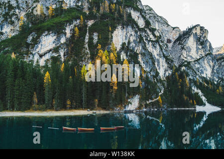 Incredibile paesaggio autunnale del lago di Lago di Braies nelle Dolomiti italiane montagne del nord Italia. In legno barche turistiche con la riflessione in acqua calma i Foto Stock