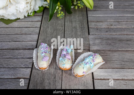 In stile tradizionale francese eclairs tipicamente viene convogliata in una forma oblunga con una sacca di tela da pasticceria Foto Stock