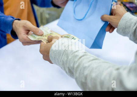 Canto dare soldi e prendere sacchetto di carta personale dal cassiere in supermercato Foto Stock