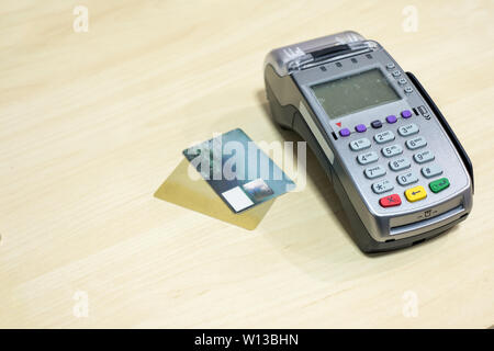 Carta di credito con il terminale di pagamento sulla scrivania in legno Foto Stock