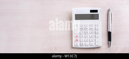 Calcolatrice di bianco e una penna luminosa sul tavolo di legno, analisi e statistiche di profitti finanziari, il rischio di investimento Concetto, copia spazio, vista dall'alto lay piatto Foto Stock