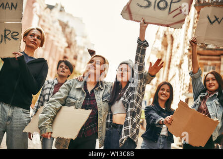 Stop alla violenza contro le donne. Un gruppo di giovani attivisti femmina sono holding cartelli con slogan diversi mentre in piedi sulla strada durante una donna marzo. Diritti dell'uomo. Concetto di protesta. Diritti delle donne Foto Stock