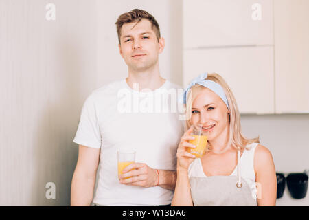 Immagine ravvicinata di bella bionda donna caucasica con il mio ragazzo tenendo il vetro con succo d'arancia appena spremuto, godendo di gustosa bevanda alla luce kitch Foto Stock