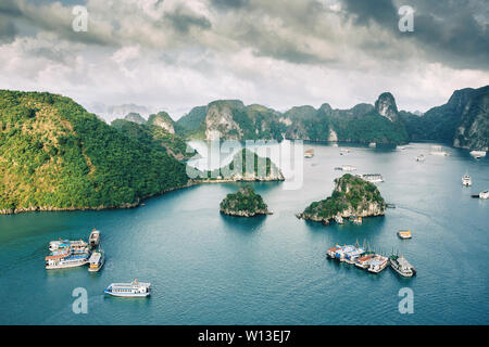 La baia di Ha Long vista panorama. Isola e rocce in mare con navi crociera intorno con tourist. Foto Stock