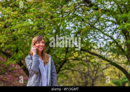 Giovane Donna che parla con il suo telefono in un parco. Foto Stock