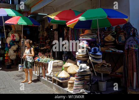 Donna in piedi turistico da un cappello store in Ubud vecchio mercato di artigianato, Bali, Indonesia Foto Stock