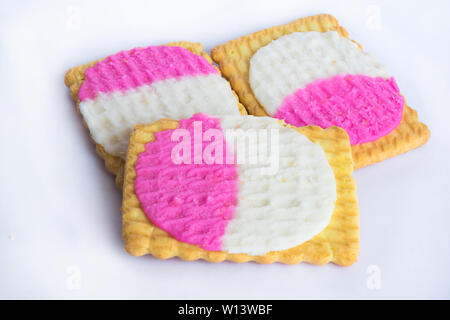 Close up di forma quadrata creme biscotti riempito di bianco e crema rosa isolato su uno sfondo bianco. Foto Stock