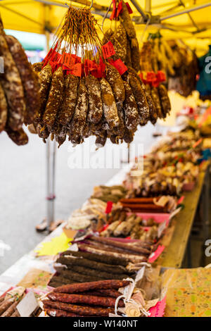 I grappoli di essiccato francese di salsicce, salami, pendente dal mercato francese in stallo. Vari tipi di salsicce indurito in mazzi. Foto Stock