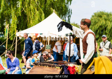 Rievocazione evento. Teatro medievale, all'aperto, uomo, mummer o player, tenendo in mano un corvo nero puppet durante l'esecuzione di un gioco per adulti e bambini. Foto Stock