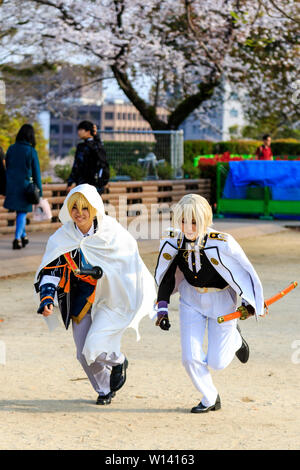 Cos Riproduci evento presso il Castello di Kumamoto Park, Giappone. Due giovani donne giapponesi in esecuzione vestita di bianco e nero unfiroms con spade dei samurai. Foto Stock