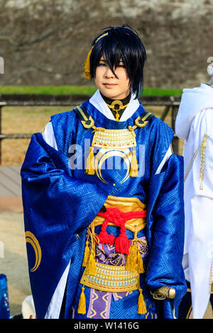 Cos Riproduci evento presso il Castello di Kumamoto Park, Giappone. Portriat di una giovane donna con gli occhi di malva indossa carattere anime samurai costume. Contatto visivo. Foto Stock