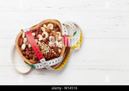 Vari dadi selezione: arachidi, nocciole, castagne, noci, pistacchi e le noci pecan su un tavolo di legno. Vista da sopra con lo spazio per il testo Foto Stock