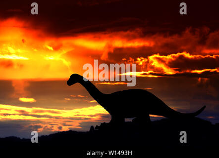 Sagome di dinosauri nella foresta sul tramonto sfondo con spazio copia consente di aggiungere del testo Foto Stock