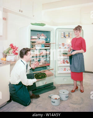 In cucina degli anni cinquanta. Una coppia giovane nella loro cucina che mostra con orgoglio il loro nuovo Frigidaire freezer. RIF BV66-4 Foto Stock