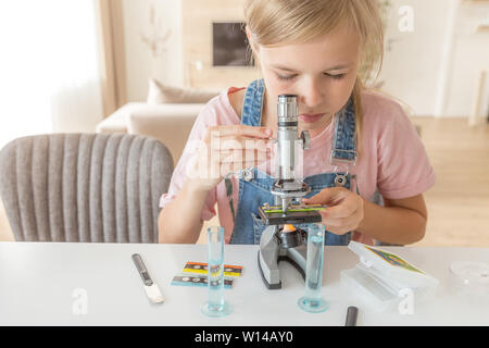 Ragazza con microscopio a imparare a casa la chimica e la riproduzione Foto Stock