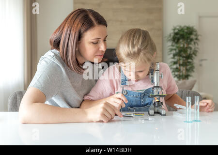 Madre e figlia giovane a fare alcuni esperimenti con microscopio a casa Foto Stock