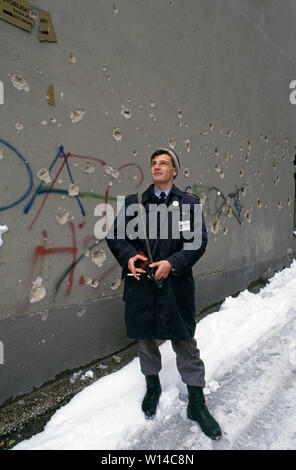 Il 28 marzo 1993 durante l'assedio di Sarajevo: un poliziotto bosniaco con il suo AK47 fucile Kalashnikov sorge nella neve contro una granata-spruzzato sulle parete in Koturova Street (off Marsala Tita Street) nella zona della città vecchia. Foto Stock