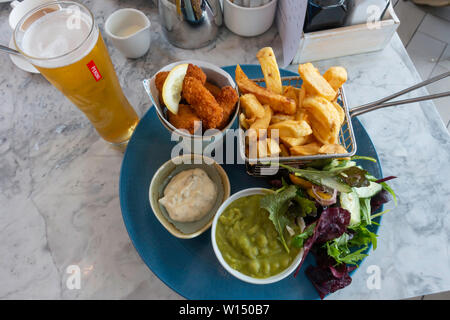 Gli scampi e i chip con giardino insalata di piselli e tartare di sugo e un bicchiere di birra Peroni al Seaview Café Saltburn in riva al mare Foto Stock