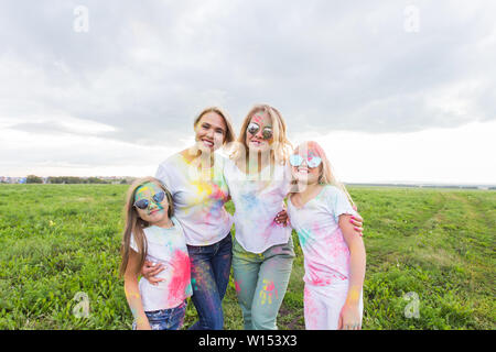 La famiglia, il festival di holi e concetto di vacanze - Close up ritratto di madri e figlie coperto di vernice. Foto Stock