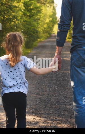 Padre e figlia passeggiate nel parco tenendo le mani. Ci sarà l'amore e prendersi cura di voi per sempre concetto.