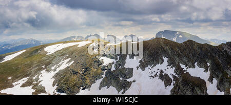 Panorama di drammatico gioco di ombre e luci su rocky montagna Rila highlands con in primo piano il reef massiccio ricoperti di neve e picchi distanti Foto Stock