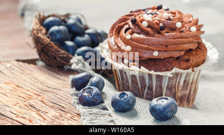 Tortini di cioccolato e crema di burro su uno sfondo di legno con mirtilli sparse Foto Stock