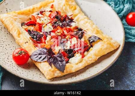 Pasta sfoglia canapes con pomodori, dolci peperoni, salame, formaggio feta e basilico viola. Close up. Foto Stock