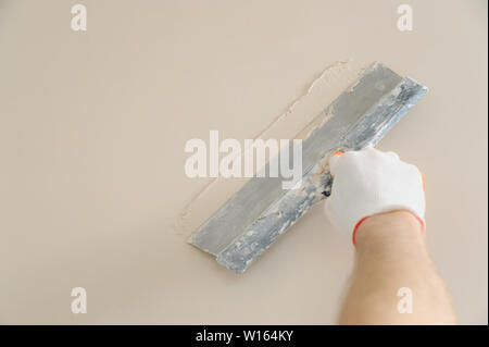 Woker la mano di intonacatura è una parete con una spatola lunga. Foto Stock