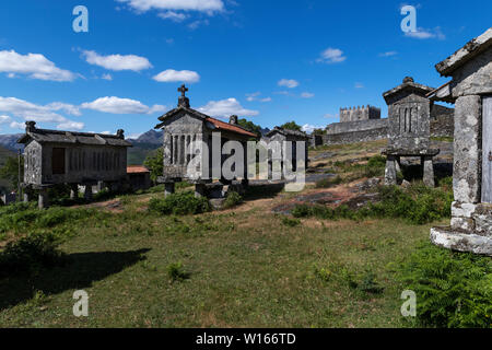 Vista dei granai (espigueiros) e castello medievale nel villaggio storico di Lindoso, Portogallo. Foto Stock
