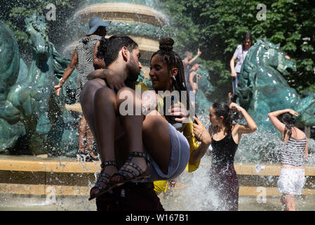 La gente si raffreddi nel Parc du Luxembourg fontana durante il Gay Pride 2019 che era su uno dei giorni più caldi dell'anno. Foto Stock