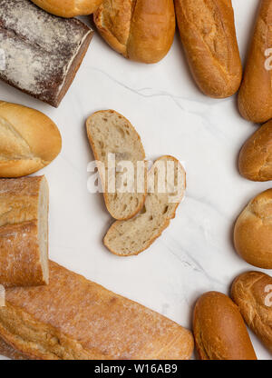 Pane al confine su marmo bianco sfondo con due fette di pane. Vista superiore, piatto laico, spazio per il testo Foto Stock